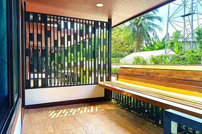 a balcony with a wooden bench and a window at Resort Thalang in Phuket