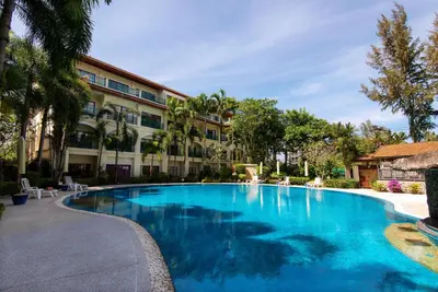 a large blue swimming pool in front of a building at Baan Puri Serviced Apartment by RESAVA in Surin Beach