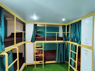 a room with four bunk beds with blue curtains at Banana Bunkhouse Hostel in Rawai Beach