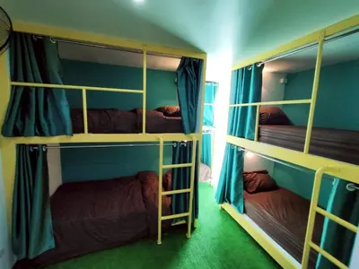 a room with three bunk beds with blue walls at Banana Bunkhouse Hostel in Rawai Beach