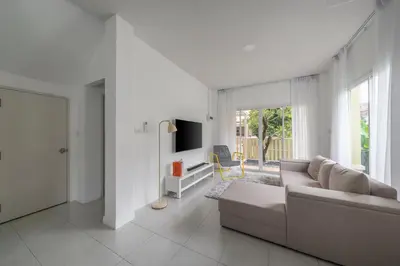 a white living room with a couch and a tv at OldTown Home Phuket 3min walk Central Festival in Ban Rangeng