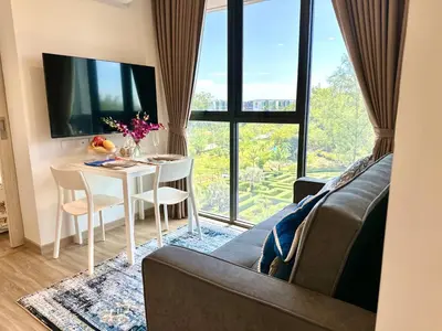 a living room with a table and a large window at Skypark Laguna 2 Bedroom Apartment in Laguna Phuket