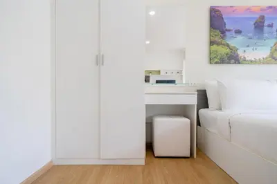 a white bedroom with a bed and a painting on the wall at Mountain view apartment near Kata beach in Kata Beach