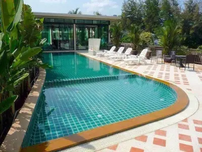 a large swimming pool with chairs and a house at Phuket Avenue in Phuket Old Town in Phuket Town