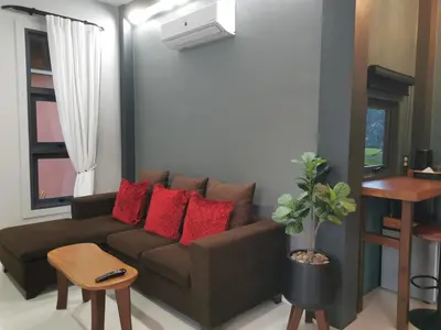 a living room with a brown couch with red pillows at Ingsala by CafeAtLuv22 in Ban Bo Rae