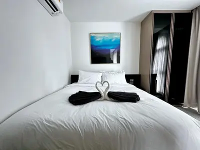 a white bed with two black robes on it at Palmetto Park Condominium in Karon Beach