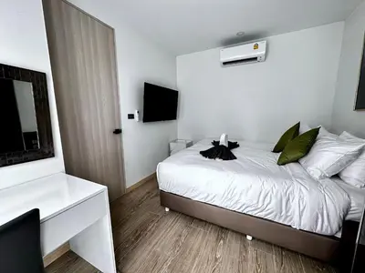 a bedroom with a bed with white sheets and green pillows at Palmetto Park Condominium in Karon Beach
