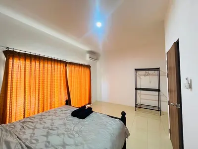 a bedroom with a bed with an orange curtain at Winlee house in Ban Phlu Yai