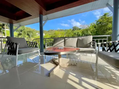 a patio with a table and chairs on a balcony at Kata Tropical Heights Villa - 4BR Private Pool in Kata Beach