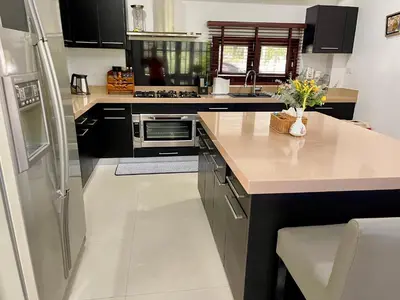 a kitchen with black cabinets and a white counter top at Kata Tropical Heights Villa - 4BR Private Pool in Kata Beach