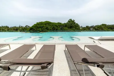 a swimming pool with two lounge chairs in front of it at Beachside 1 bedroom apartment 200 meters to Bang Tao Beach Manage by OCEAN HUB in Ban Thalat Choeng Thale