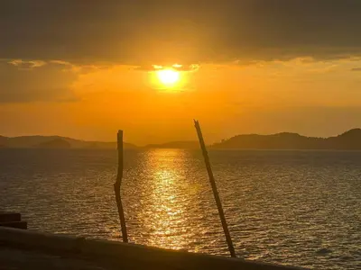 a boat in the ocean with the sunset in the background at THE REAL ESCAPE - Koh Yao Noi in Ko Yao Noi