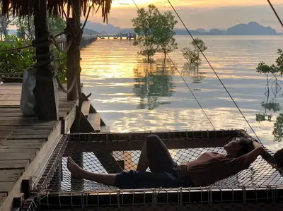 a man laying on a hammock next to the water at THE REAL ESCAPE - Koh Yao Noi in Ko Yao Noi