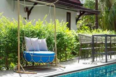 a swinging chair next to a swimming pool at Howard Johnson by Wyndham Phuket Naiyang in Thalang