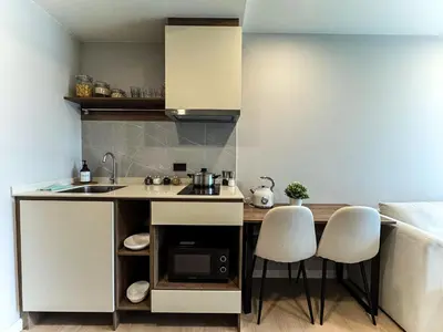 a kitchen with a sink and two white chairs at New Stylish Cozy One-bedroom Apartment in Bangtao, Phuket, Near EDC in Ban Thalat Choeng Thale
