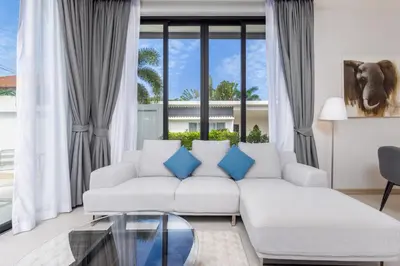 a living room with a white couch and blue pillows at Villa Noa Modern 2-Bedroom with Private Pool in Rawai Beach