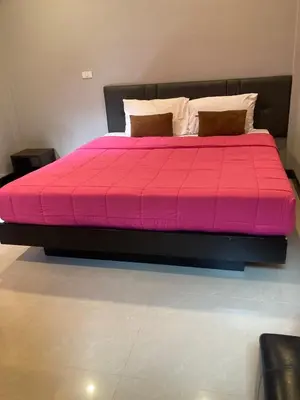 a large bed with a pink comforter in a room at Saiinam Laguna Inn in Ban Thalat Choeng Thale