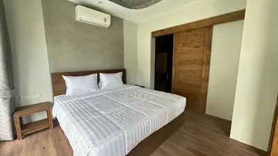 a bedroom with a bed with white sheets and a wooden door at Villa avec piscine privée in Kamala Beach