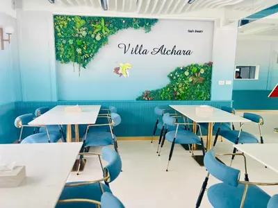 a dining room with tables and blue chairs at Villa Atchara in Patong Beach