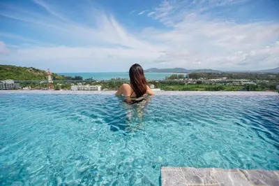 a woman sitting in the water in a swimming pool at 1 bedroom Mida Grande Resort, Phuket in Surin Beach