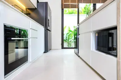 a kitchen with white floors and black appliances at Lerka Villa Elegant 3 Bedroom in Rawai Beach