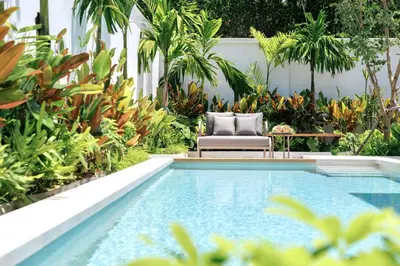 a pool in a garden with a chair and plants at Lerka Villa Elegant 3 Bedroom in Rawai Beach