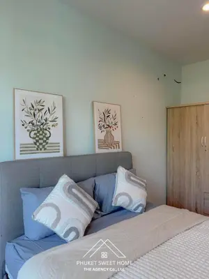 a bedroom with a bed with blue and white pillows at THe bell chalong phuket 19 in Ban Klang