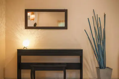 a mirror on a wall with a table and a lamp at Areca Holiday Home 1, Bangtao Beach in Ban Thalat Choeng Thale