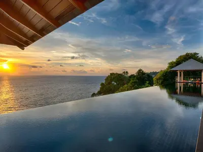 a swimming pool with a sunset over the water at Baan Paa Talee Estate - SHA Extra Plus in Kamala Beach