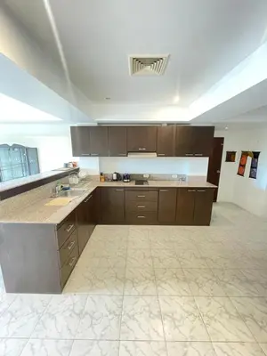 a large kitchen with brown cabinets and a tile floor at Rawai Condominium in Ban Saiyuan (1)