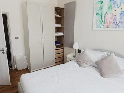 a bedroom with a white bed and a painting on the wall at FAMILY HOMES - Brand New 2BDRM Poolside Apartment in Phuket