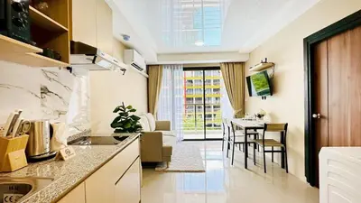 a kitchen and living room with a table and chairs at Cozy condo maikhao Phuket in Ban Mai Salae