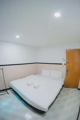 a large white bed in a room with a wooden door at XX Mitr Inn Phuket Oldtown in Phuket Town