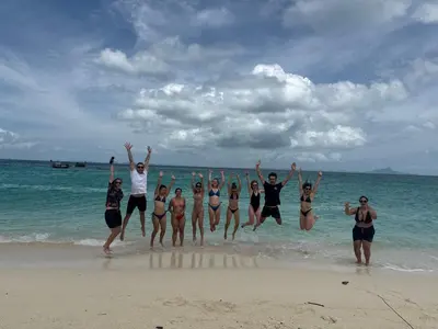 a group of people jumping in the water on the beach at Global Beach Hostel - Ao Nang in Ban Khlong Haeng