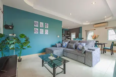 a living room with a couch and a blue wall at Areca Holiday Home 7, Bangtao Beach in Ban Thalat Choeng Thale