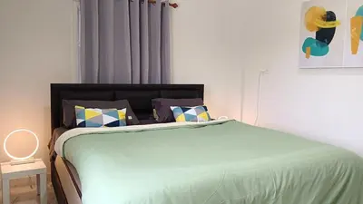 a bedroom with a bed with a green comforter and pillows at Best Bliss, Bangtao Beach in Ban Thalat Choeng Thale