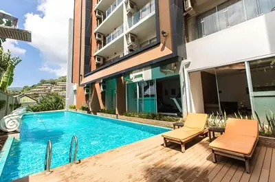 a swimming pool in the middle of a building with two chairs at CHIC CONDO - Best mountain view near Karon beach in Karon Beach