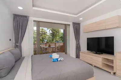 a bedroom with a large bed and a flat screen tv at Studio Apartment - Nakalay Palm in Kamala Beach