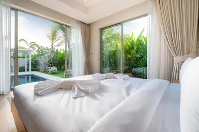 a white bed in a bedroom with a large window at Trichada Tropical - 3 Bedrooms Pool Villa in Laguna Phuket