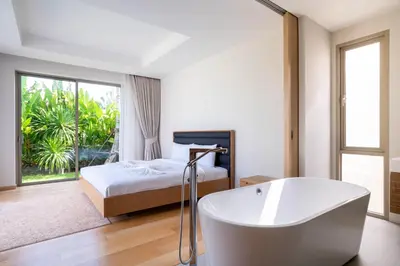 a bedroom with a bath tub and a bed with a window at Trichada Tropical - 3 Bedrooms Pool Villa in Laguna Phuket