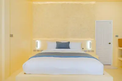 a bedroom with a white bed with a blue pillow at Loft with pool - 8min walk to Rawai Beach - 