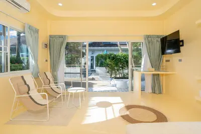 a living room with yellow walls and a tv and chairs at Loft with pool - 8min walk to Rawai Beach - 