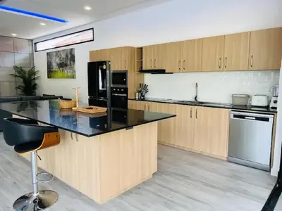 a kitchen with wooden cabinets and a black counter top at Joy Villa - Luxury 4 bedroom villa in Ban Saiyuan (1)