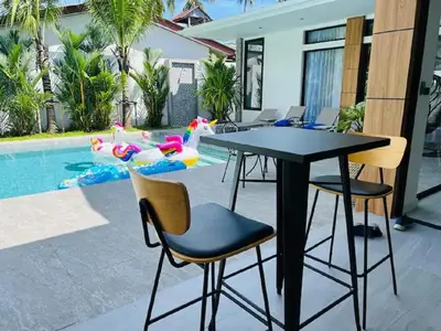 a black table and chairs next to a swimming pool at Joy Villa - Luxury 4 bedroom villa in Ban Saiyuan (1)