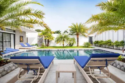 a swimming pool with blue chairs and palm trees at Pattana Moon - Luxury Calm 4 Bedrooms Pool Villa in Ban Saiyuan (1)