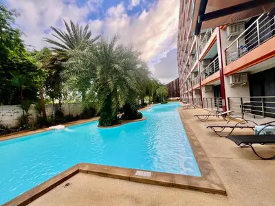 a large blue swimming pool next to a building at Cozy Condotel Maikhao in Mai Khao Beach