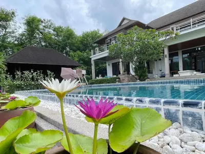a house with a swimming pool with a purple and white flower at Kiri Anda Villa Phuket in Rawai Beach