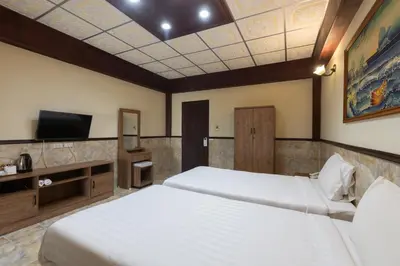 a hotel room with two beds and a tv at Kata Palace Phuket Hotel in Kata Beach