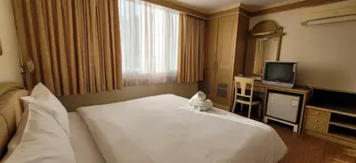 a hotel room with a white bed and a television at Neptuna Kata Beach in Kata Beach