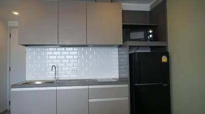 a kitchen with a black refrigerator and white cabinets at Urban Tide Studio T3 -626 in Chalong